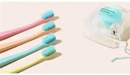 Pastel toothbrushes arranged next to a container of coconut oil woven dental floss for plaque removal and fresh breath.